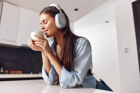 Женщина наслаждается музыкой и кофе в уютной атмосфере, окружённая расслаблением и комфортом