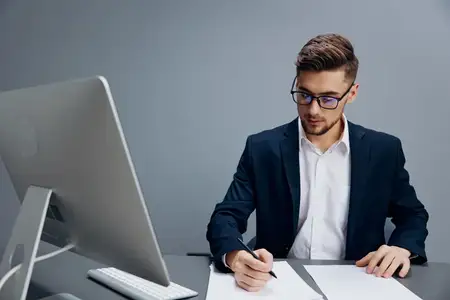 Бизнесмен в очках работает за компьютером в офисе