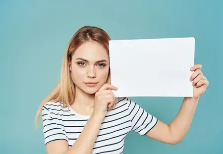 Женщина спряталась за белым листом бумаги с рекламным баннером