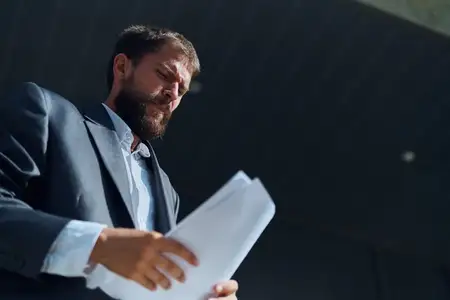 Бизнесмен на улице с документами в руках возле здания, официальный стиль жизни