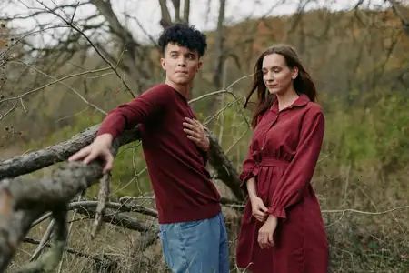 Насыщенный осенний пейзаж с мягким пасмурным светом обрамляет искреннюю связь между двумя людьми, тонкий язык тела и правдоподобное взаимодействие подчеркивают достоверность и реалистичную атмосферу