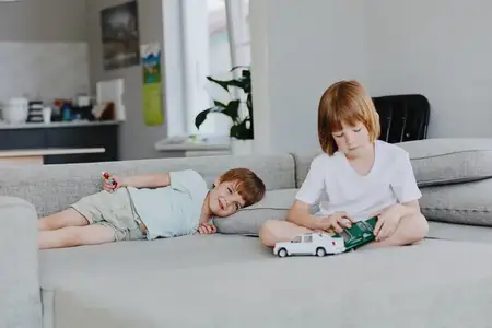 В светлой гостиной два мальчика наслаждаются игрой с игрушечными машинками