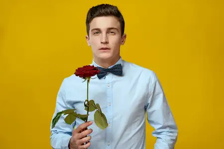 Джентльмен в рубашке и бабочке на жёлтом фоне с красной розой