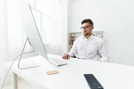 Бизнесмен в очках сидит за столом в офисе, работает, руководитель
