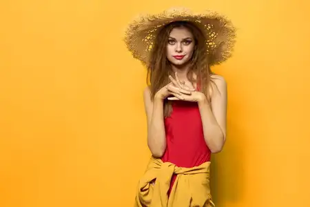 Женщина в соломенной шляпе с ярким макияжем, летний образ жизни, веселье на желтом фоне