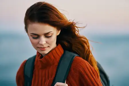 Женщина, женщина-туристка с рюкзаком возле моря в горах на природе, модель в красном свитере