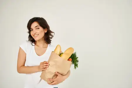 Симпатичная брюнетка с пакетом продуктов из супермаркета для доставки