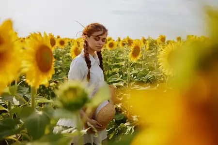 Девушка с косичками смотрит на подсолнуховое поле