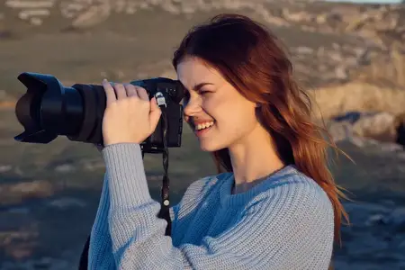 Женщина-профессиональный фотограф на открытом воздухе, занимается хобби и работой, на фоне пейзажа