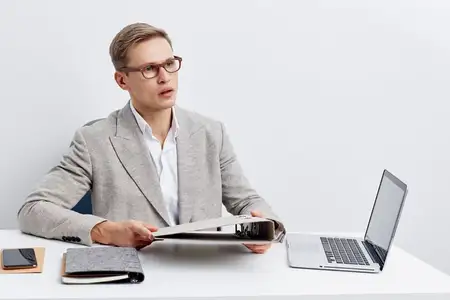 Бизнесмен в официальной одежде и очках работает за современным столом с ноутбуком