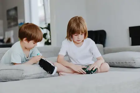 Сцена с девочкой и мальчиком, увлеченными воображаемой игрой с игрушечными машинками и гаджетами, подчеркивающая их творческое взаимодействие и теплоту семейной обстановки