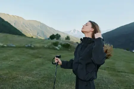 Человек наслаждается широким открытым пейзажем с горами и лугами