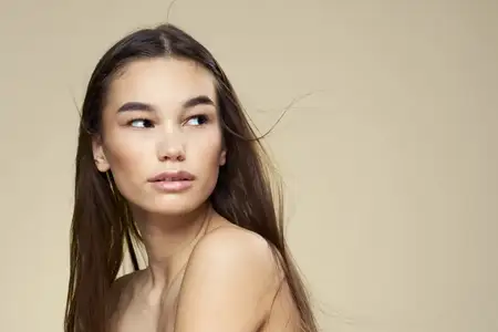 Красивая женщина с обнажёнными плечами на бежевом фоне