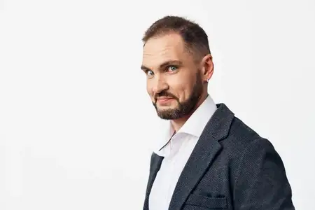 Он передает решимость и готовность, слегка улыбаясь, но оставаясь собранным, с острым костюмом и чистыми линиями, которые отражают лидерство, экспертизу и надежную работу