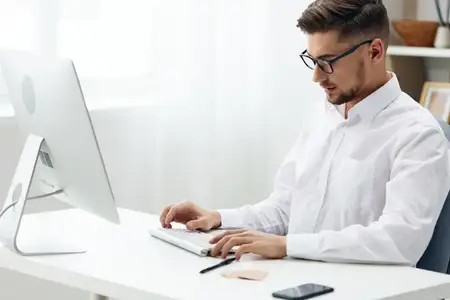 Бизнесмен в очках сидит за столом в офисе, работает, руководитель