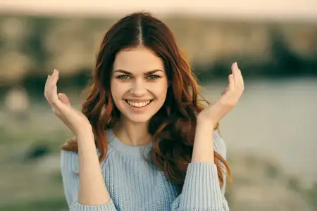 Симпатичная рыжеволосая женщина на фоне скалистых гор на открытом воздухе, полная эмоций