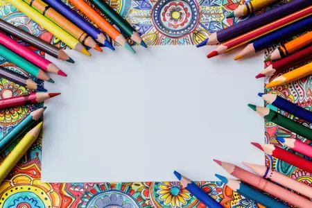 Яркий ассортимент мелков и цветных карандашей, окружающих чистый лист бумаги, для творческого вдохновения и художественного самовыражения