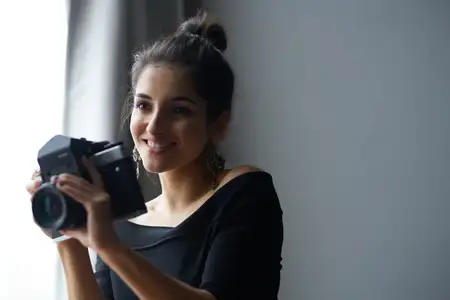Счастливая женщина-фотограф в помещении, силуэт модели в вечернем платье
