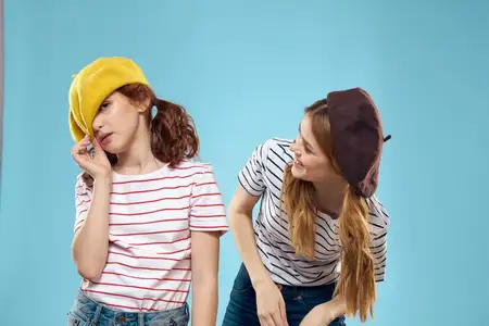 Модные сёстры в шляпах, весёлый образ жизни, студийная съёмка на синем фоне