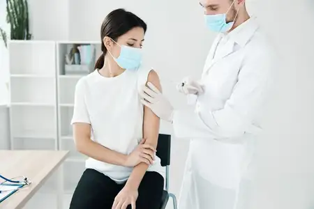 Пациентка получает вакцинацию от COVID-19 в больнице, врач в медицинской маске
