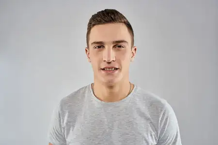 Крупный план красивого мужчины в светлой футболке, передающий эмоции на изолированном студийном фоне