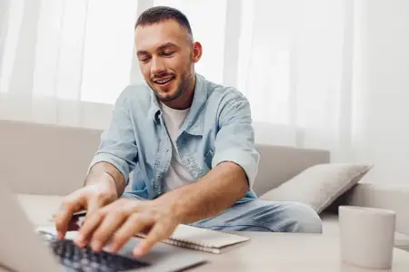 Веселый мужчина занимается удаленной работой, удобно устроившись дома