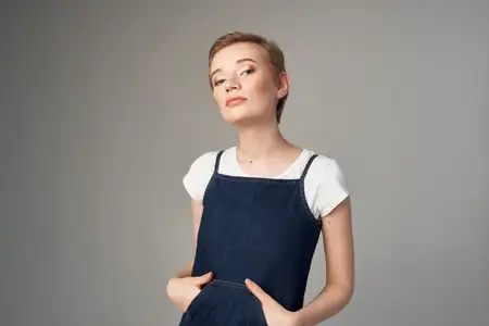 Красивая женщина позирует, выражая эмоции и веселье, с прической на светлом фоне