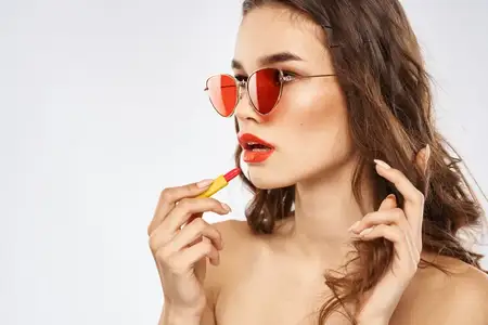 Модная брюнетка в солнцезащитных очках с макияжем и помадой