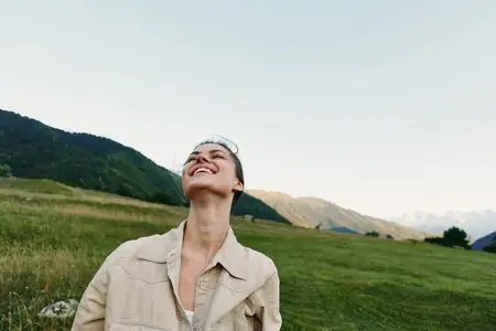 Портрет жизнерадостной женщины в повседневной верхней одежде, наслаждающейся открытой сельской местностью, голубое небо и открытый ландшафт