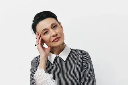 Счастливая азиатская женщина с рукой, лежащей на голове, улыбается; портрет позитивной молодой девушки