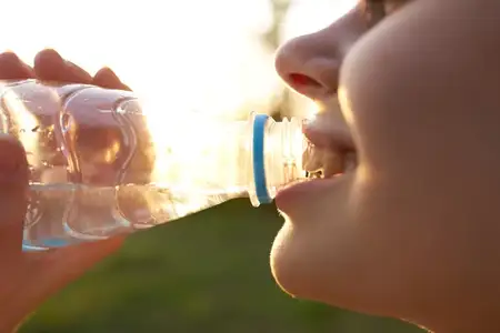 Женщина пьет воду из бутылки, крупный план лица, лето