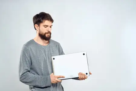 Эмоциональный мужчина держит ноутбук, успех, современный стиль, работа на светлом фоне
