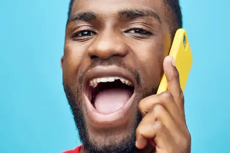 Молодой человек улыбается, глядя на экран смартфона