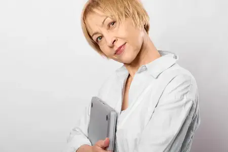 Пожилая женщина с короткими светлыми волосами держит смартфон
