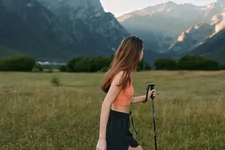 Активный турист прогуливается по открытому полю к далеким вершинам, наслаждаясь свежим воздухом, теплым светом и природной красотой мирного пейзажа