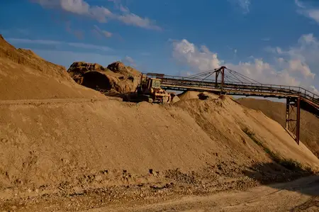 Железный бульдозер работает на строительстве моста, занимаясь выемкой грунта на песчаной дороге в промышленной зоне