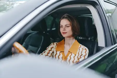 Спокойное, уверенное настроение с естественным дневным светом и кинематографичным освещением, подчеркивающим сосредоточенность и стиль во время одиночной поездки
