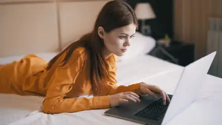 Женщина лежит в кровати перед ноутбуком, фриланс, работа в интернете
