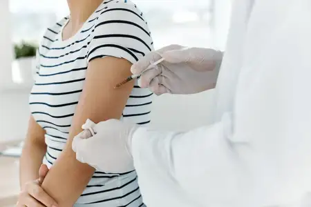 Врач-мужчина в белом халате делает пациенту укол в плечо