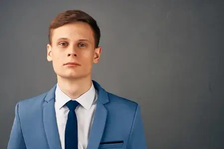 Уверенный в себе деловой мужчина в костюме с галстуком позирует на изолированном фоне