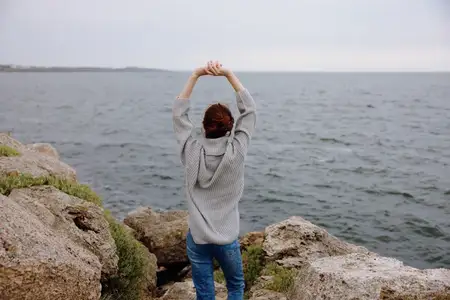 Красивая женщина на каменистом побережье во время туристической поездки в облачную погоду