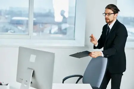 Бизнесмен сидит за рабочим столом с компьютером в офисе, стиль лайфстайл