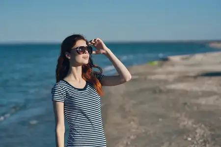 Симпатичная путешественница в футболке отдыхает на пляже в горах у реки во время летнего отпуска