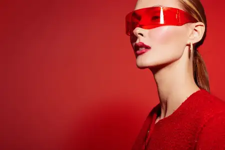 Модная женщина в красном козырьке и красном наряде стоит на красном фоне