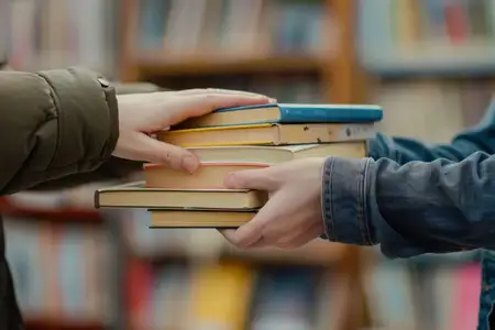 Руки держат стопку книг на фоне библиотечного стеллажа