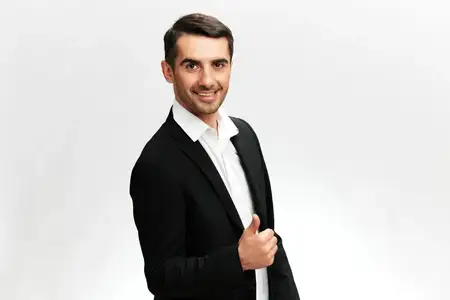 Менеджер в стильном костюме улыбается, позирует с чувством уверенности в себе, на изолированном фоне