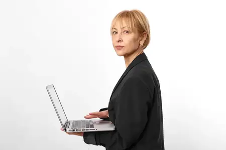 Зрелая пожилая женщина в деловом костюме работает за ноутбуком