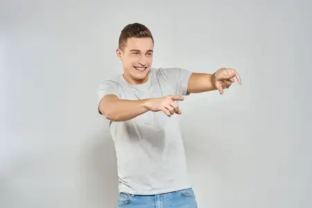 Красивый мужчина в светлой футболке, снятый крупным планом, демонстрирует эмоции на изолированном студийном фоне
