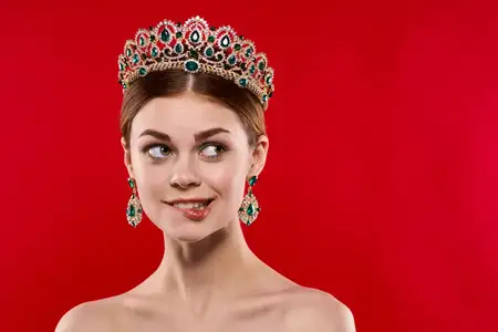 Красивая женщина с роскошными обнаженными плечами, косметика, мода, веселье на красном фоне