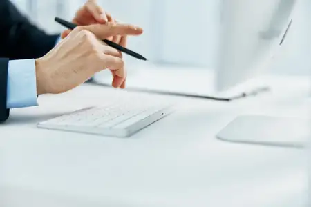 Мужчина работает за компьютером на рабочем столе в офисе, используя клавиатуру